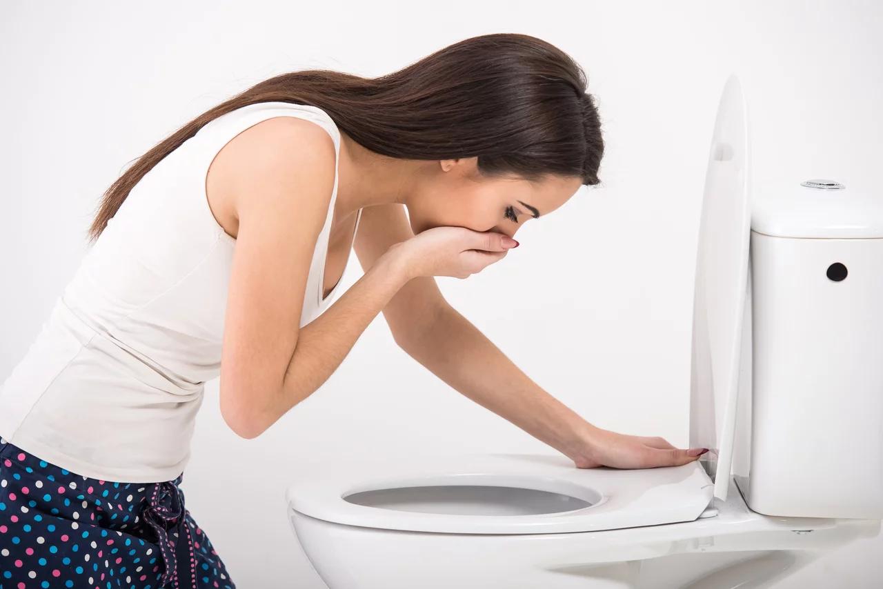 Young woman vomiting into the toilet